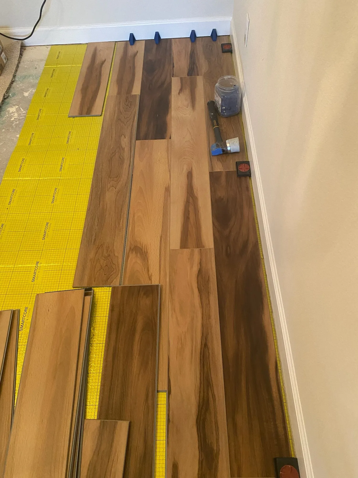 Vinyl planks being laid over underlayment along a wall