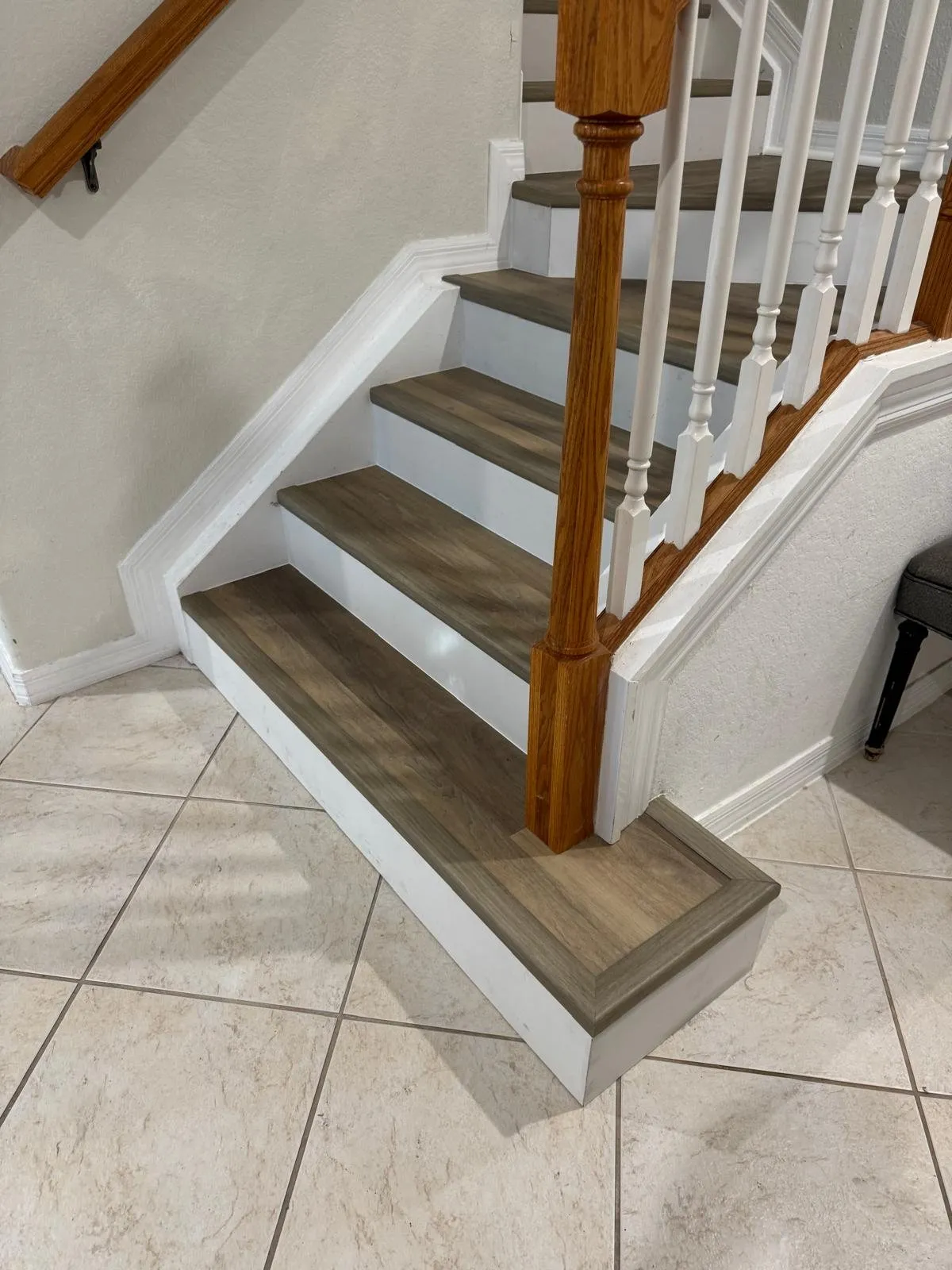Bottom steps with gray oak vinyl treads around a wood newel post